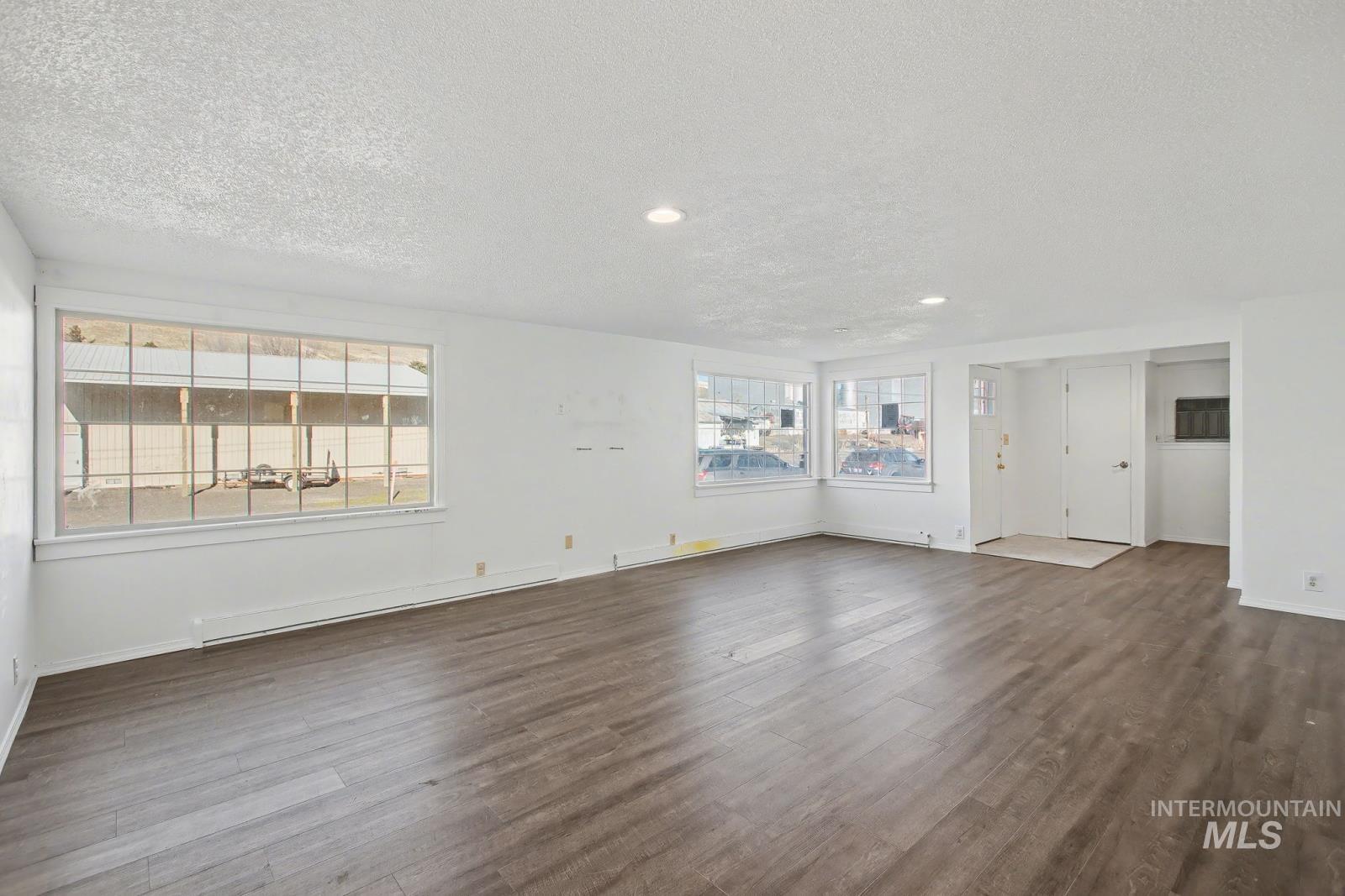 1830 Columbia Street Pomeroy, WA 99347 - Photo 5 of 28 Unfurnished living room featuring a textured ceiling, dark wood finished floors, a baseboard heating unit, and recessed lighting