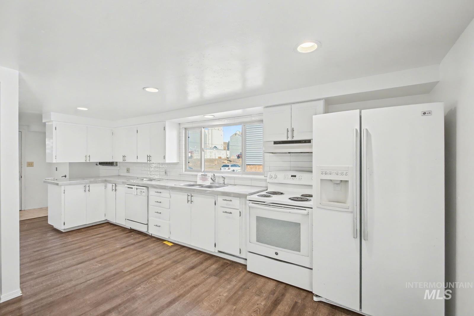 1830 Columbia Street Pomeroy, WA 99347 - Photo 8 of 28 Kitchen with white appliances, white cabinetry, decorative backsplash, light countertops, and dark wood-style floors