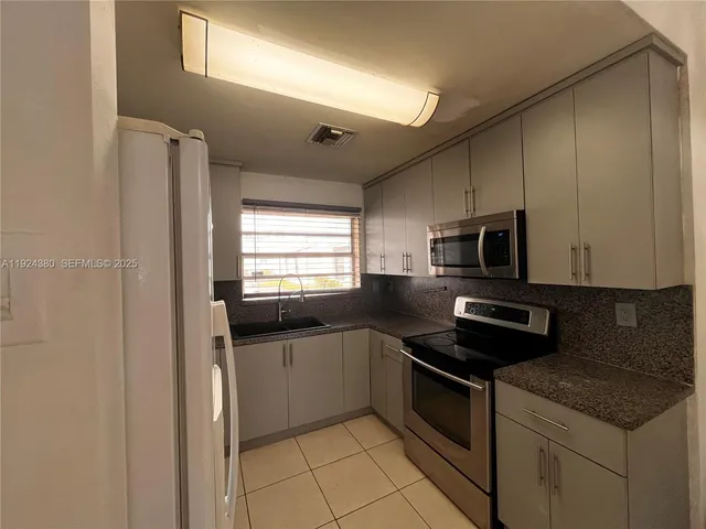 a kitchen with stainless steel appliances granite countertop a stove a sink and a microwave
