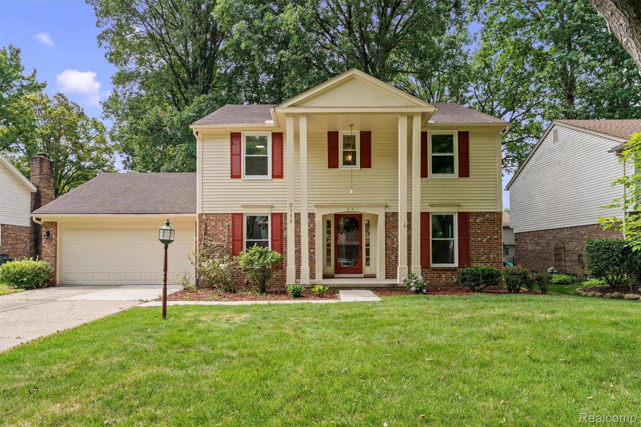 2118 Rutgers Drive Troy, MI 48085 - Photo 1 of 39 Traditional two-story home featuring a brick and siding exterior, a prominent portico with columns, and a two-car attached garage