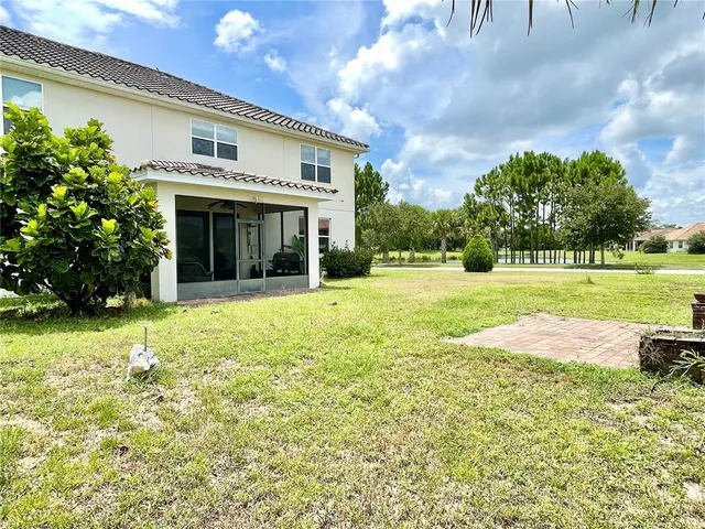 a view of a house with a yard and large trees