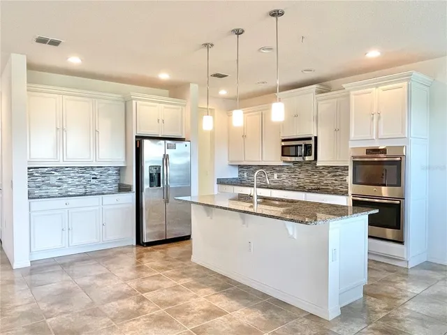 a kitchen with stainless steel appliances granite countertop a stove a sink and a refrigerator