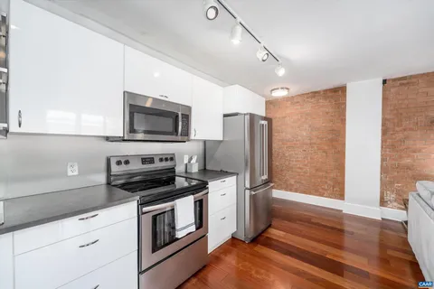 a large kitchen with stainless steel appliances granite countertop a stove and a wooden floors