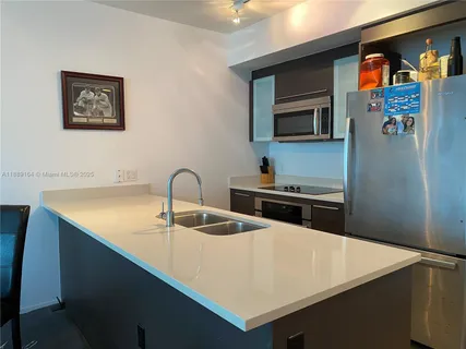 a kitchen with stainless steel appliances a sink dishwasher a refrigerator and a stove with wooden floor