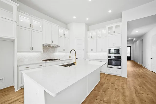 a kitchen with stainless steel appliances a sink a stove and a wooden floors