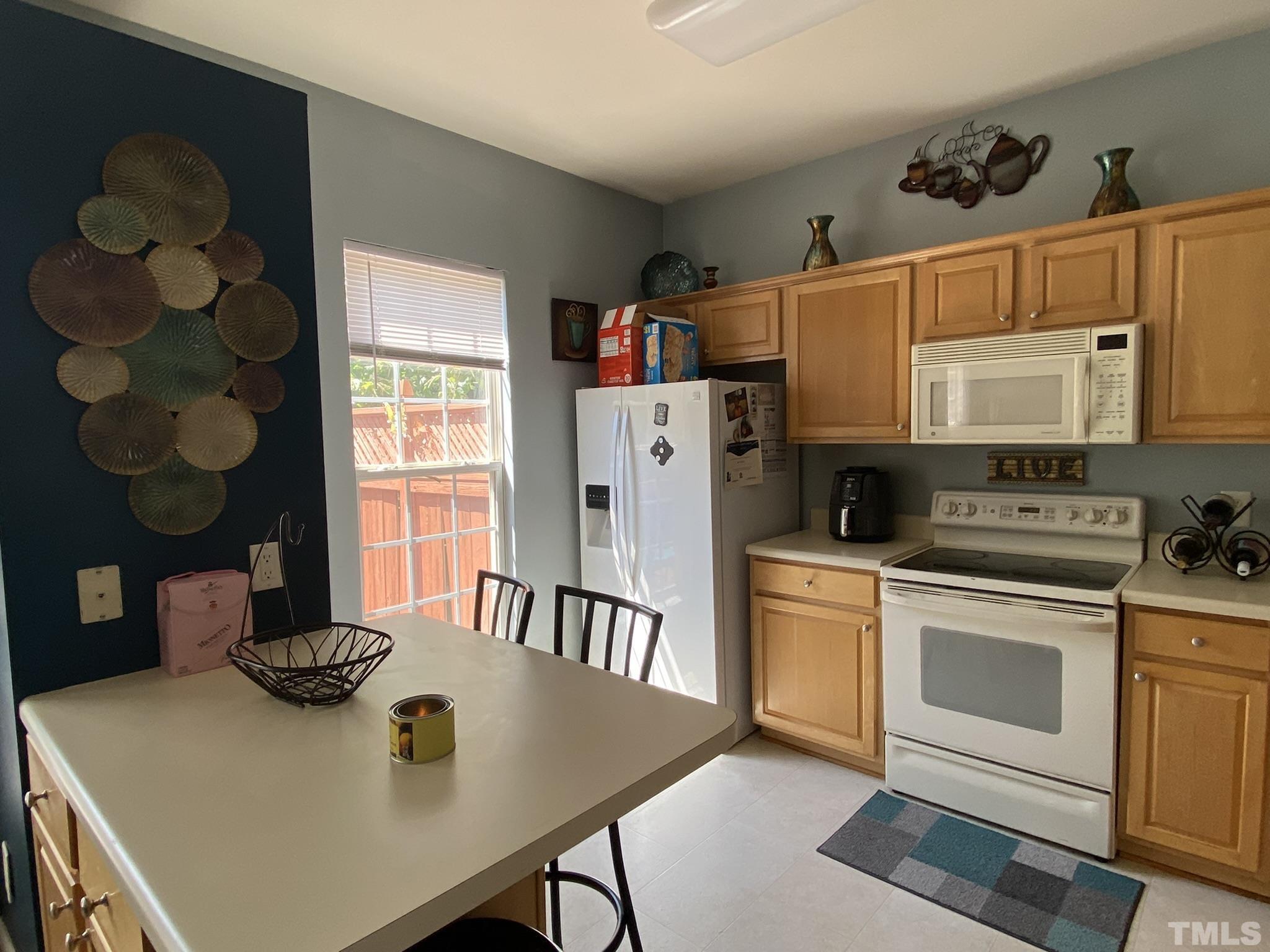 7251 Galon Glen Road Raleigh, NC 27613 - Photo 9 of 26 a kitchen with stainless steel appliances granite countertop a stove a refrigerator a microwave a dining table and chairs with wooden floor