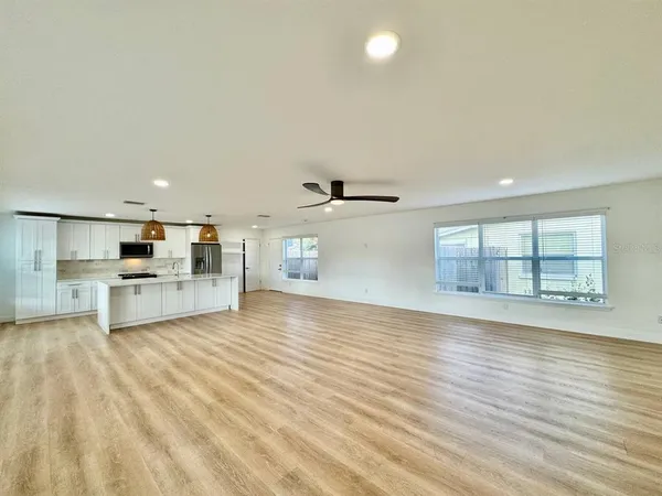 a view of empty room with wooden floor and kitchen view