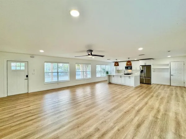 a view of an empty room with wooden floor and a window
