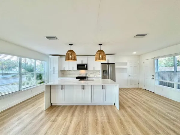 a view of a kitchen with wooden floor and electronic appliances