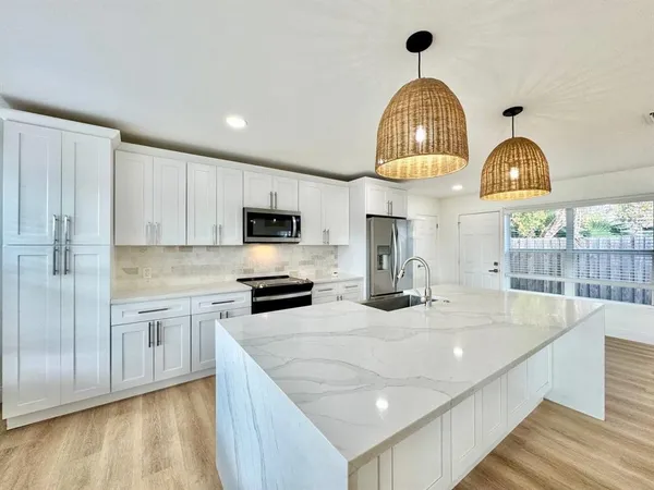 a kitchen with stainless steel appliances granite countertop a sink a stove and a wooden floors