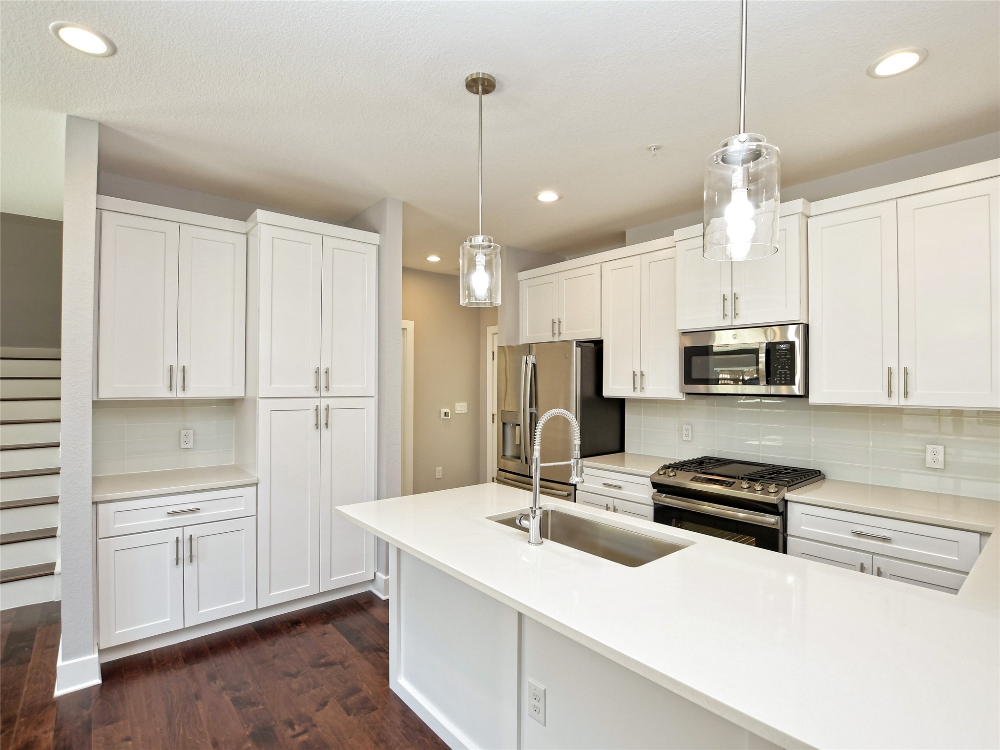 1130 Lott Avenue, Unit B Austin, TX 78721 - Photo 11 of 29 Kitchen with stainless steel appliances, white cabinets, decorative light fixtures, dark wood-style flooring, and backsplash