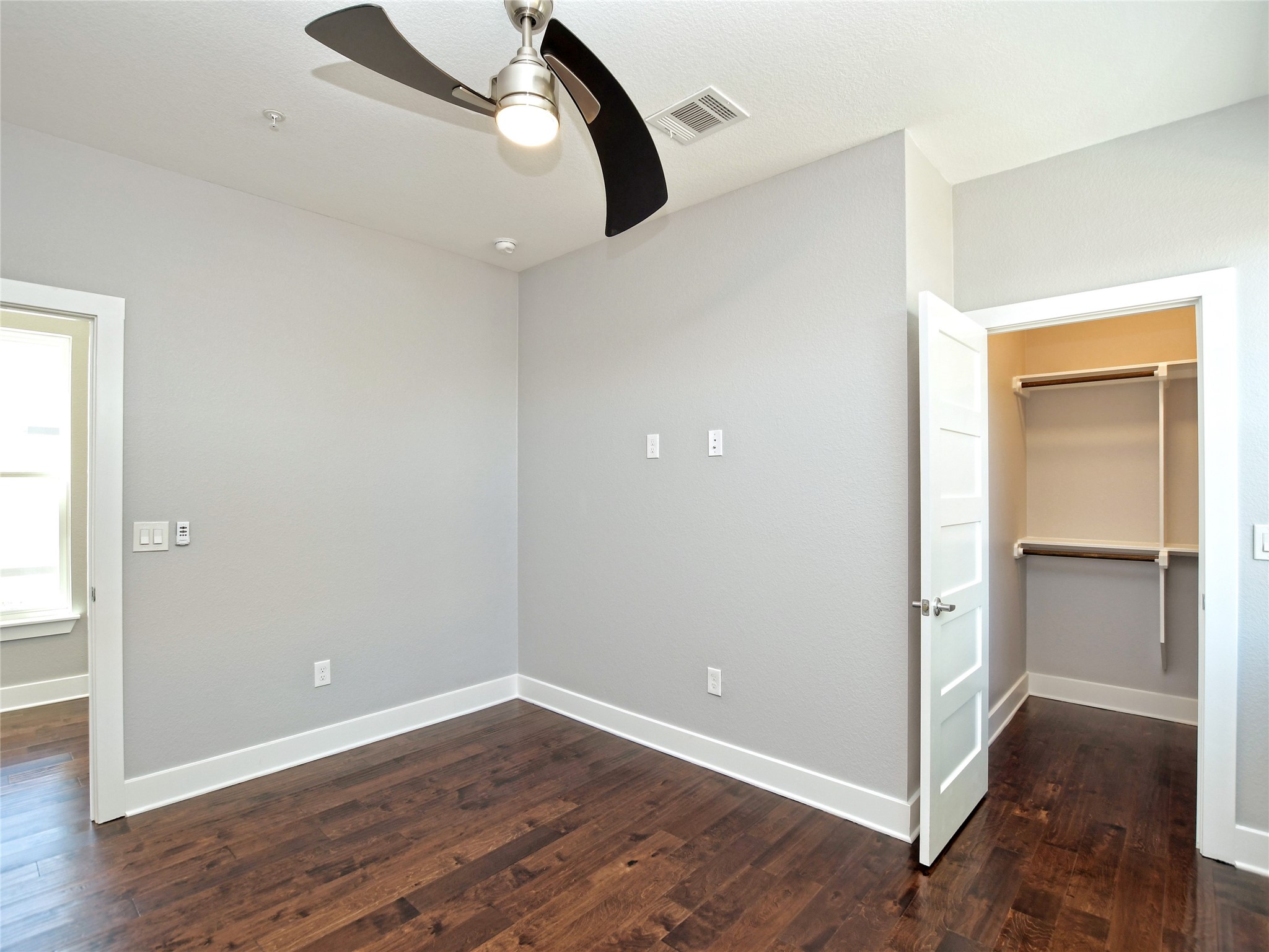 1130 Lott Avenue, Unit B Austin, TX 78721 - Photo 26 of 29 Unfurnished bedroom featuring a spacious closet, dark wood-type flooring, and a ceiling fan