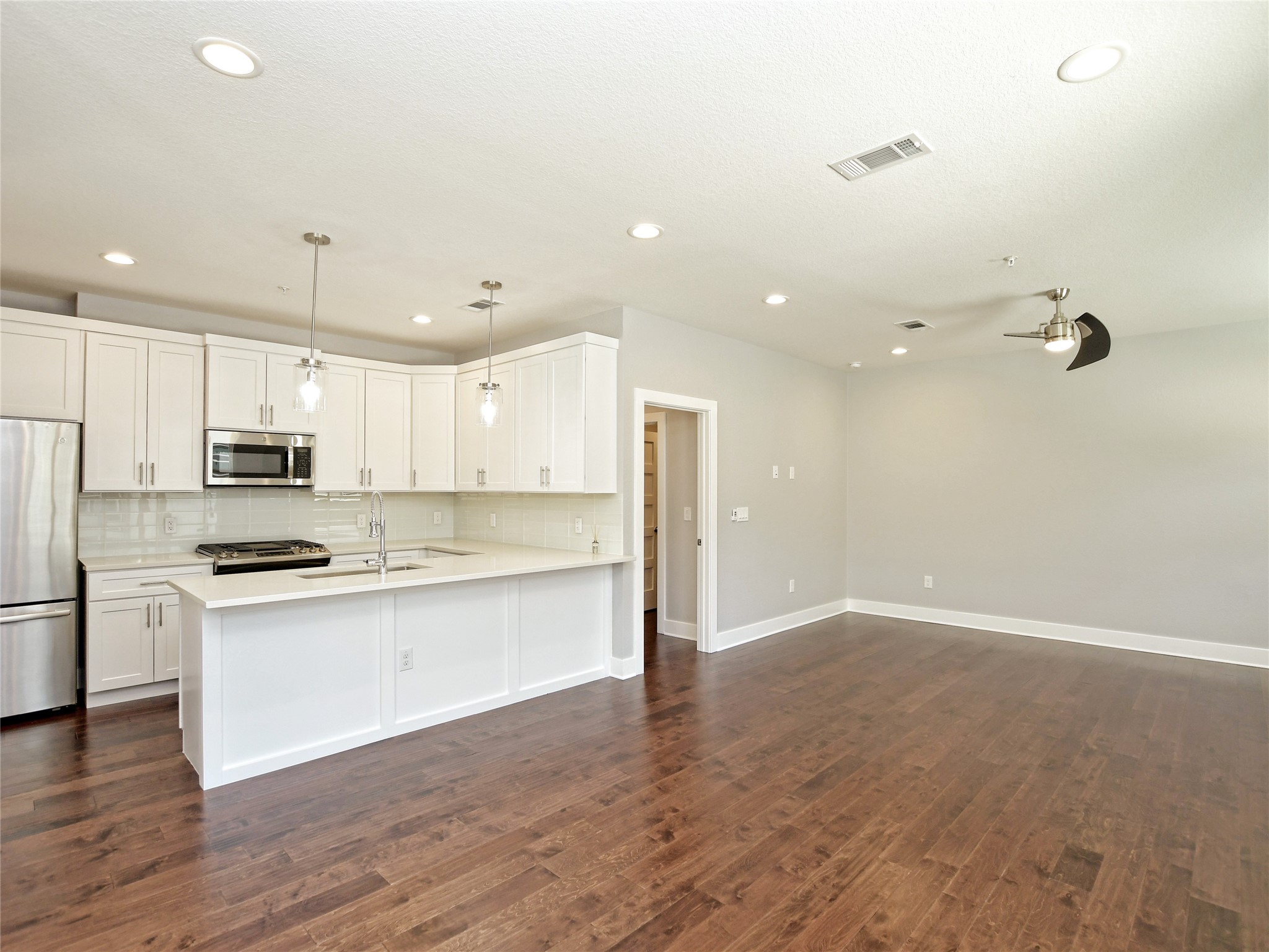 1130 Lott Avenue, Unit B Austin, TX 78721 - Photo 29 of 29 Kitchen featuring stainless steel appliances, open floor plan, white cabinetry, dark wood finished floors, and hanging light fixtures