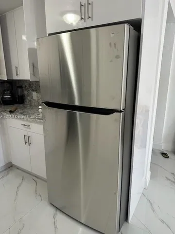 a view of a refrigerator with white cabinets