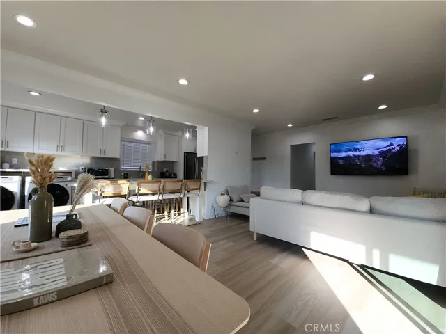 a living room with stainless steel appliances furniture a rug and a view of kitchen
