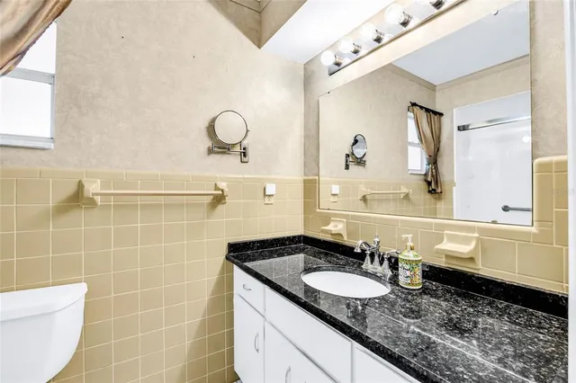 a bathroom with a granite countertop sink a mirror and a shower