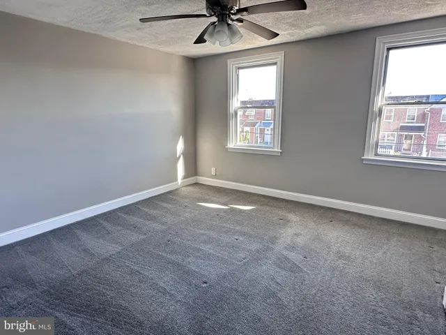 an empty room with a window and a fan
