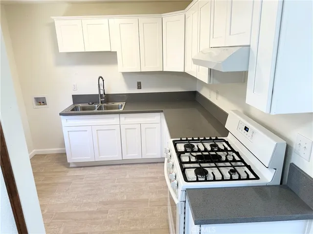 a kitchen with granite countertop a sink stove and cabinets