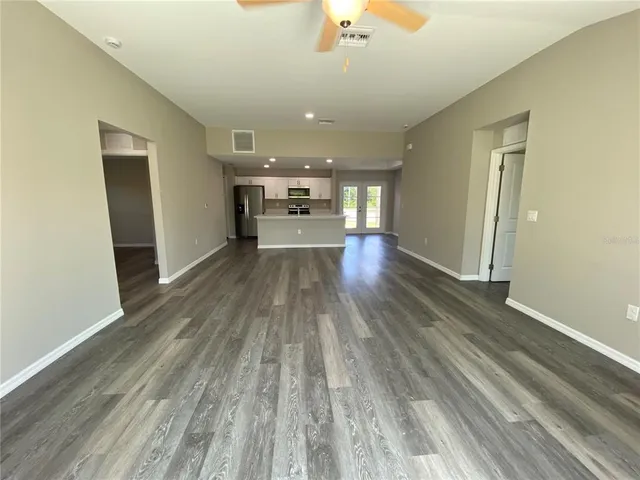 wooden floor in an empty room with a kitchen