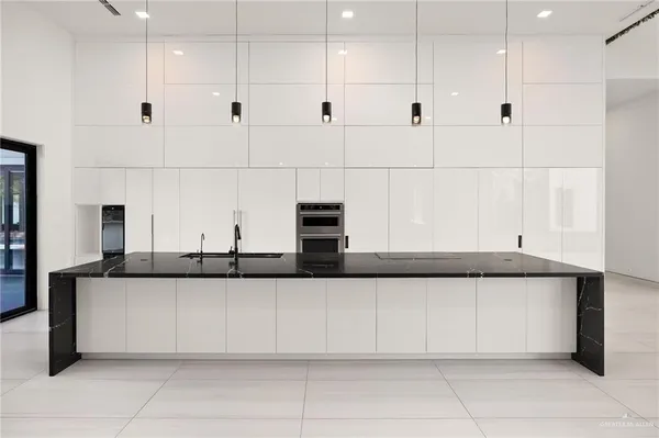 a large white kitchen with a large window stainless steel appliances