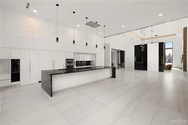 a large white kitchen with stainless steel appliances a large counter top and a stove