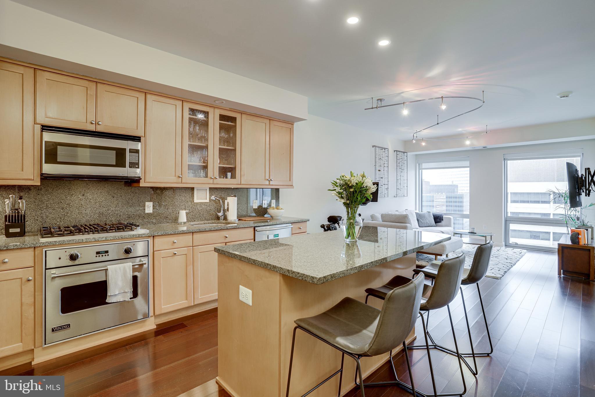 1111 19th Street North, Unit 1706 Arlington, VA 22209 - Photo 1 of 15 a kitchen with stainless steel appliances kitchen island granite countertop a stove a sink dishwasher and microwave with wooden floor
