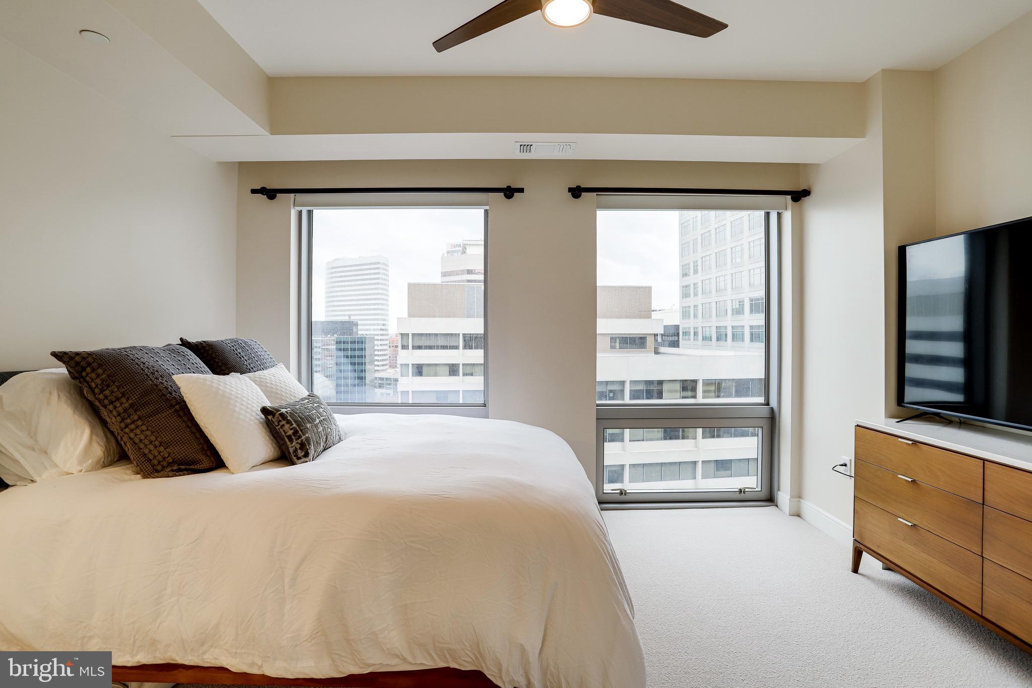 1111 19th Street North, Unit 1706 Arlington, VA 22209 - Photo 7 of 15 a bedroom with a large bed and a flat tv screen on dresser