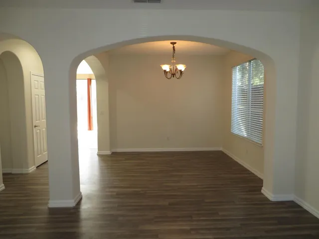 an empty room with wooden floor and chandelier