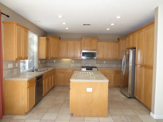 a kitchen with stainless steel appliances granite countertop a sink stove refrigerator and cabinets