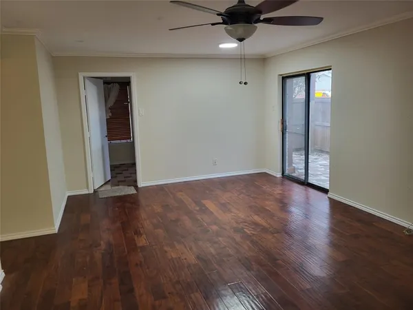 a view of an empty room with wooden floor and a ceiling fan