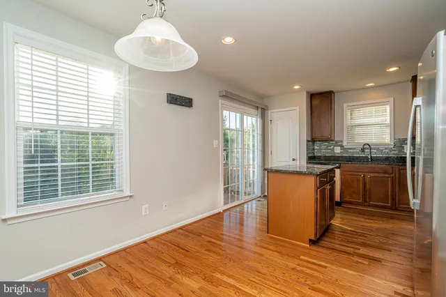 a kitchen with granite countertop a stove a sink dishwasher a refrigerator and white cabinets with wooden floor