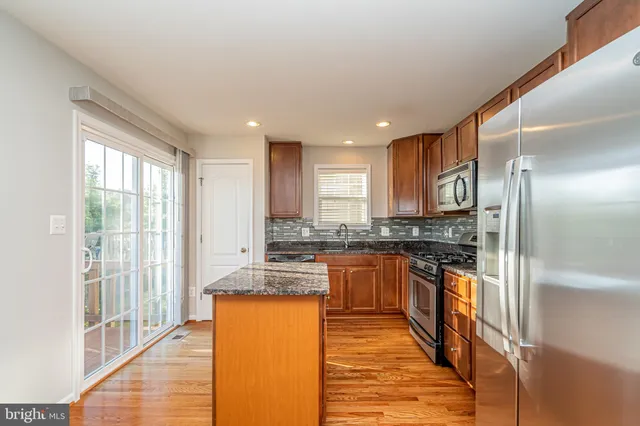 a large kitchen with stainless steel appliances granite countertop a large counter top a stove and a refrigerator