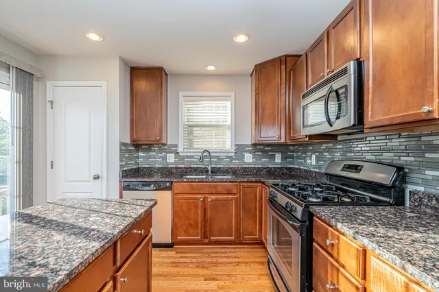 a kitchen with stainless steel appliances granite countertop stove top oven microwave and cabinets