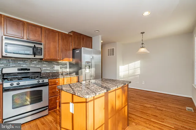 a kitchen with granite countertop wooden cabinets stainless steel appliances and a counter space