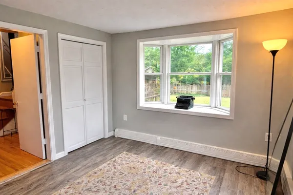 a view of a bedroom with wooden floor and white walls