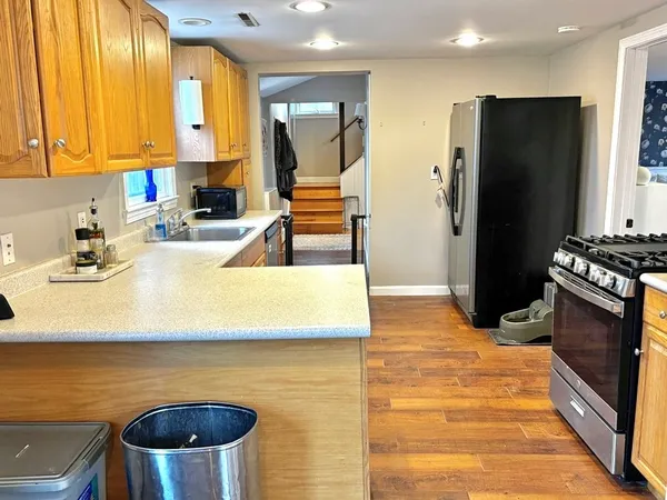 a kitchen with granite countertop wooden cabinets a sink and dishwasher next to a window