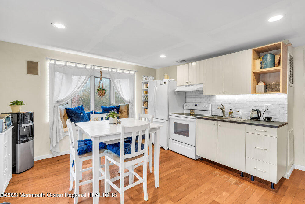 1064 Maxim Southard Road Howell, NJ 07731 - Photo 23 of 40 a kitchen with granite countertop a table chairs stove and white cabinets