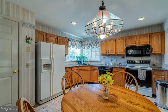 a kitchen with stainless steel appliances granite countertop a refrigerator a stove top oven a sink dishwasher and dining table with wooden floor