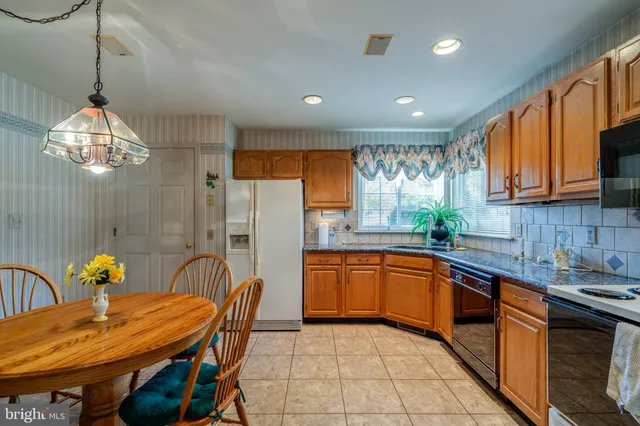 a kitchen with stainless steel appliances granite countertop a sink dishwasher a stove a kitchen island with dining table and chairs