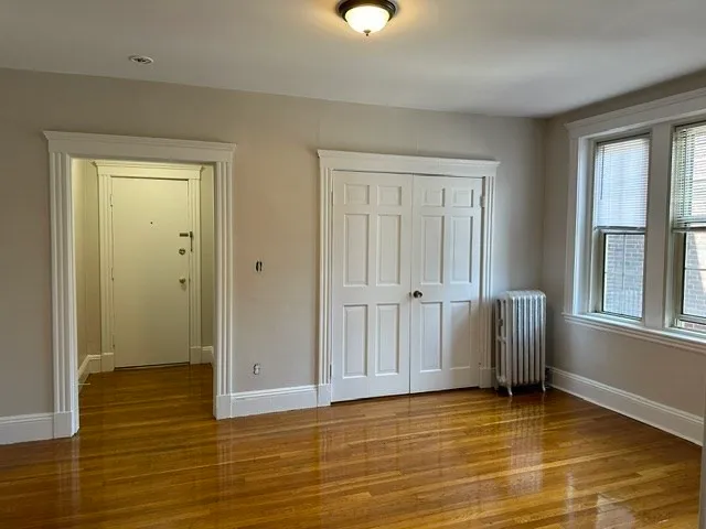 a view of an empty room with window and wooden floor