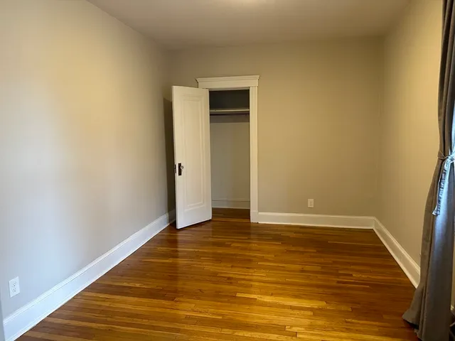 a view of an empty room with closet and a window
