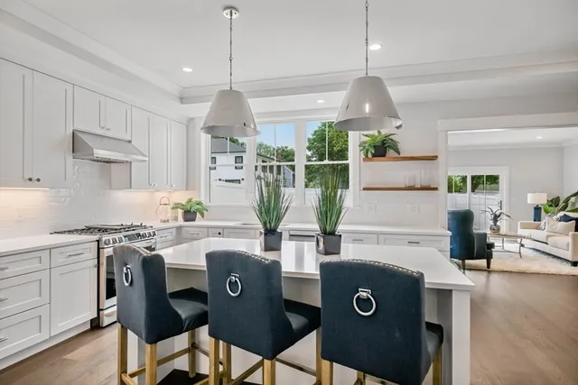 a kitchen with stainless steel appliances granite countertop a stove a refrigerator a sink dishwasher and white cabinets with wooden floor