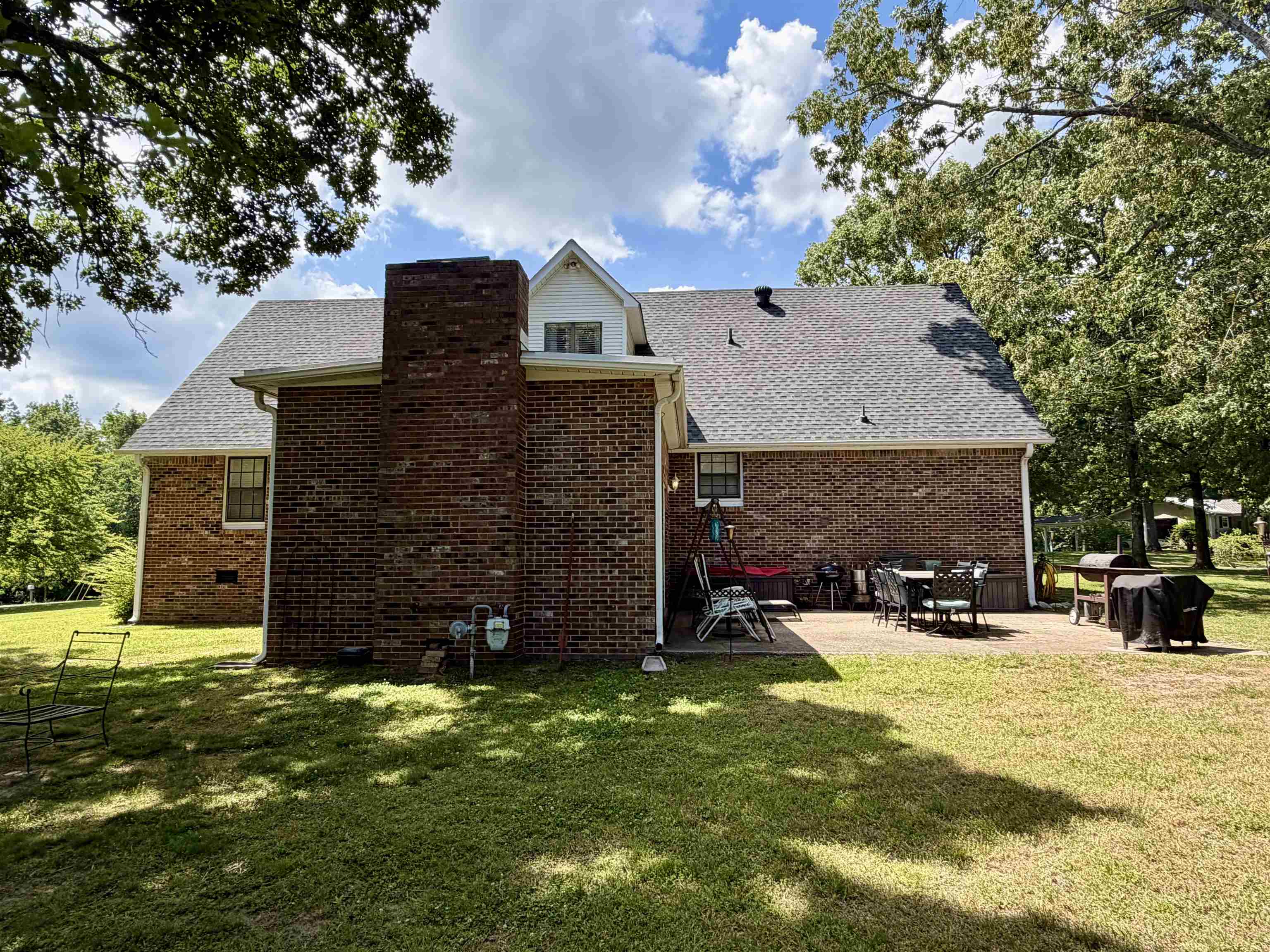 142 Treece Street Selmer, TN 38375 - Photo 28 of 36 Brick exterior featuring a prominent chimney, gray shingle roof, and a dormer window