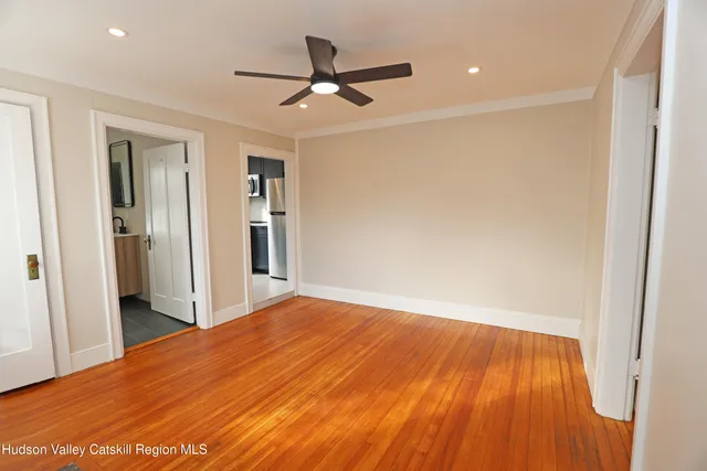 a view of a big room with wooden floor and a ceiling fan