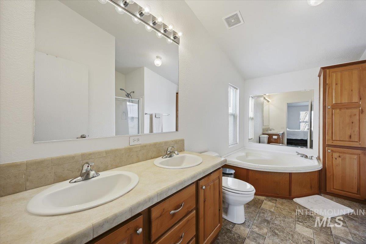 1014 S Highway Albion, ID 83311 - Photo 21 of 34 Full bathroom with double vanity, a bath, a shower stall, stone finish flooring, and vaulted ceiling