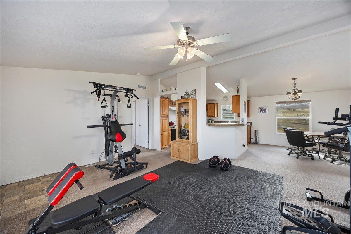 1014 S Highway Albion, ID 83311 - Photo 4 of 34 Exercise area featuring carpet flooring, vaulted ceiling with beams, stone finish floors, and ceiling fan
