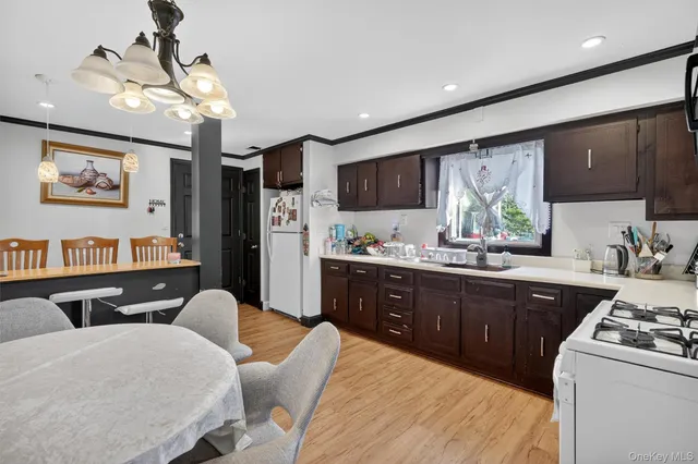 a kitchen with stainless steel appliances granite countertop a refrigerator a sink dishwasher a dining table and chairs with wooden floor