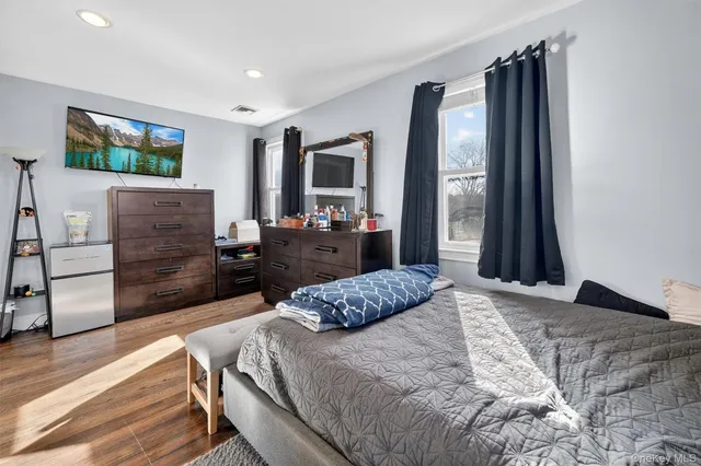 a bedroom with a bed table flat screen tv and a window