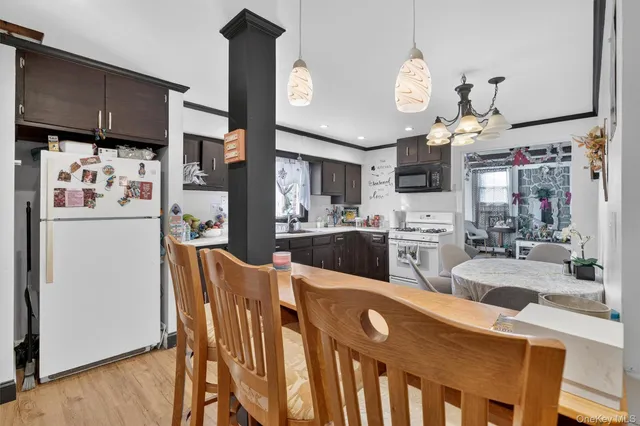 a kitchen with stainless steel appliances granite countertop a sink a stove a refrigerator cabinets and chairs