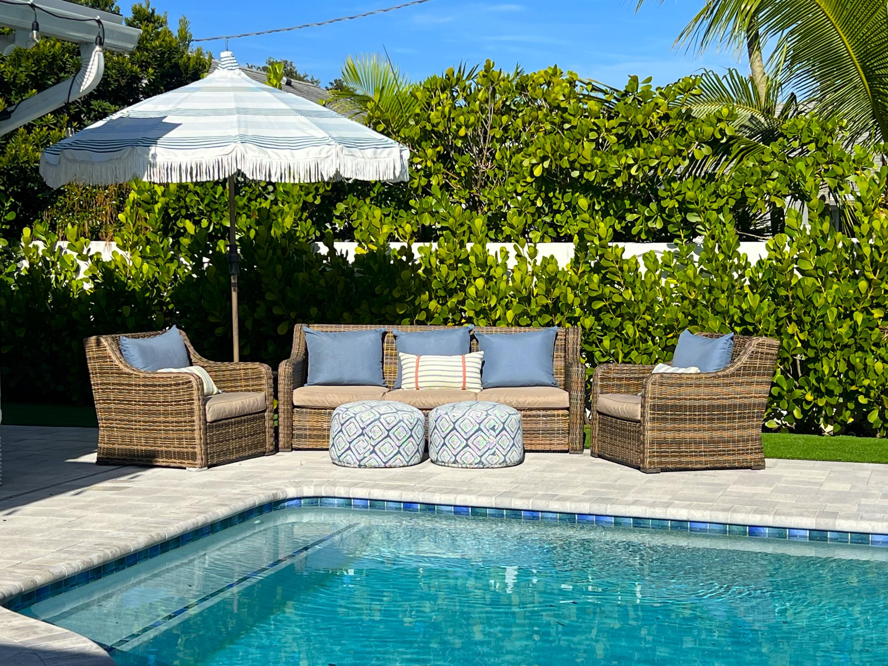 342 Country Club Drive Tequesta, FL 33469 - Photo 2 of 67 a view of a patio with couches table and chairs under an umbrella